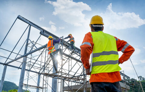 Engineer technician watching team of workers on high steel platform.